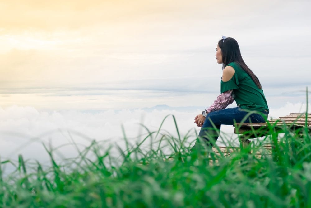 A woman being mindful and sitting by the water