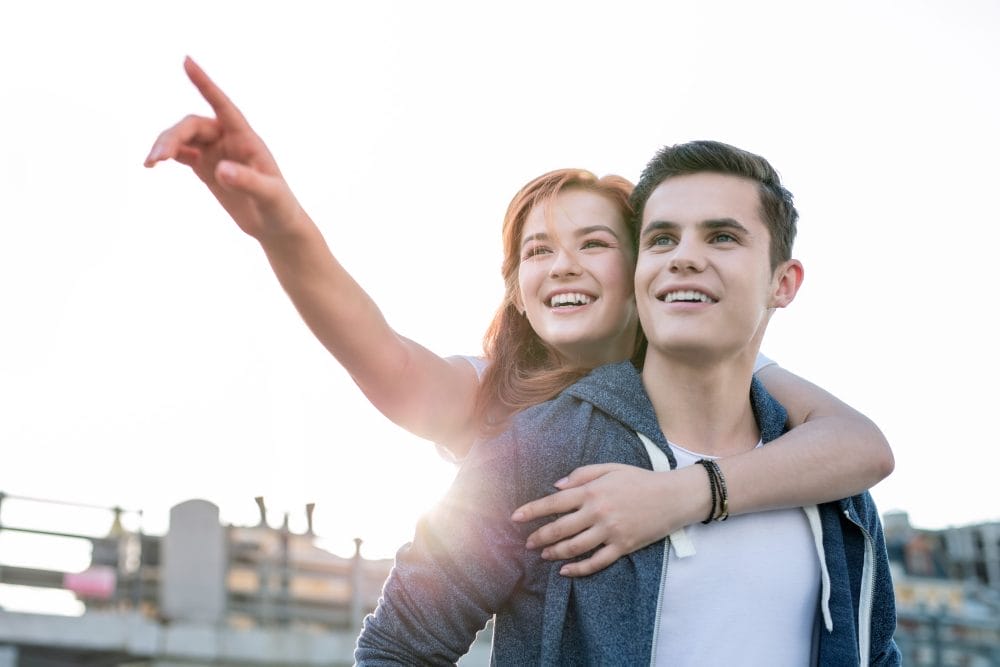 Happy woman holding her boyfriend and pointing