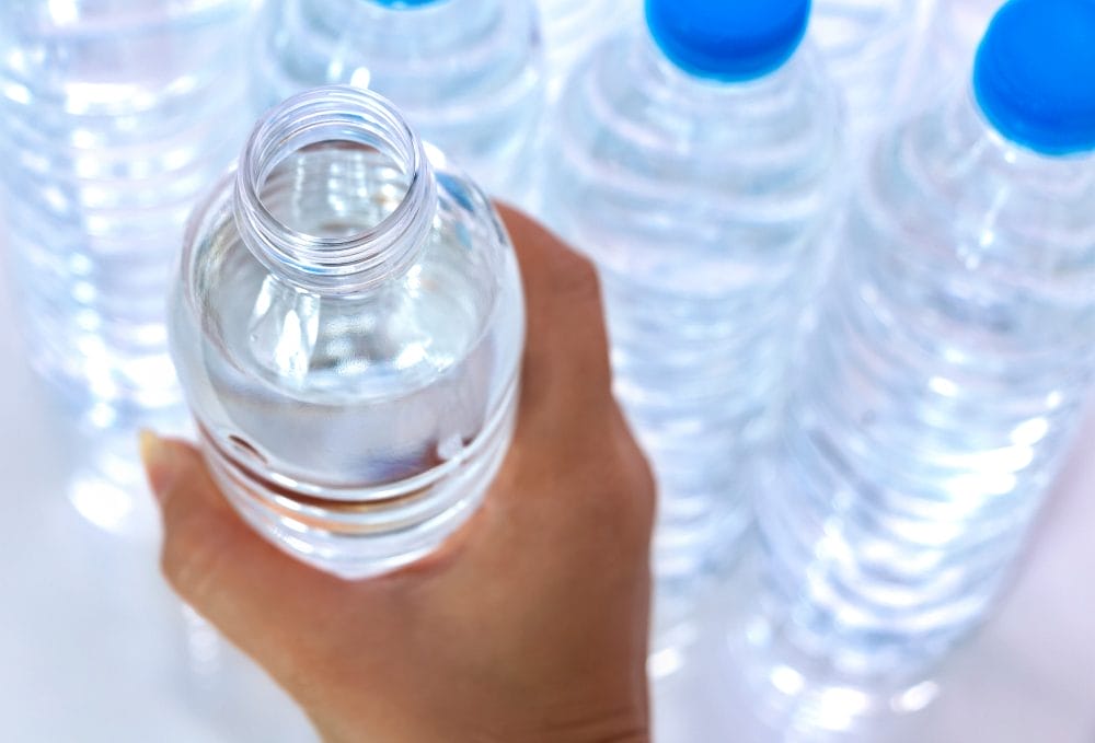 Women's hands picked up plastic water bottles that are open the lid was removed. Water helps to quench their thirst and heat.