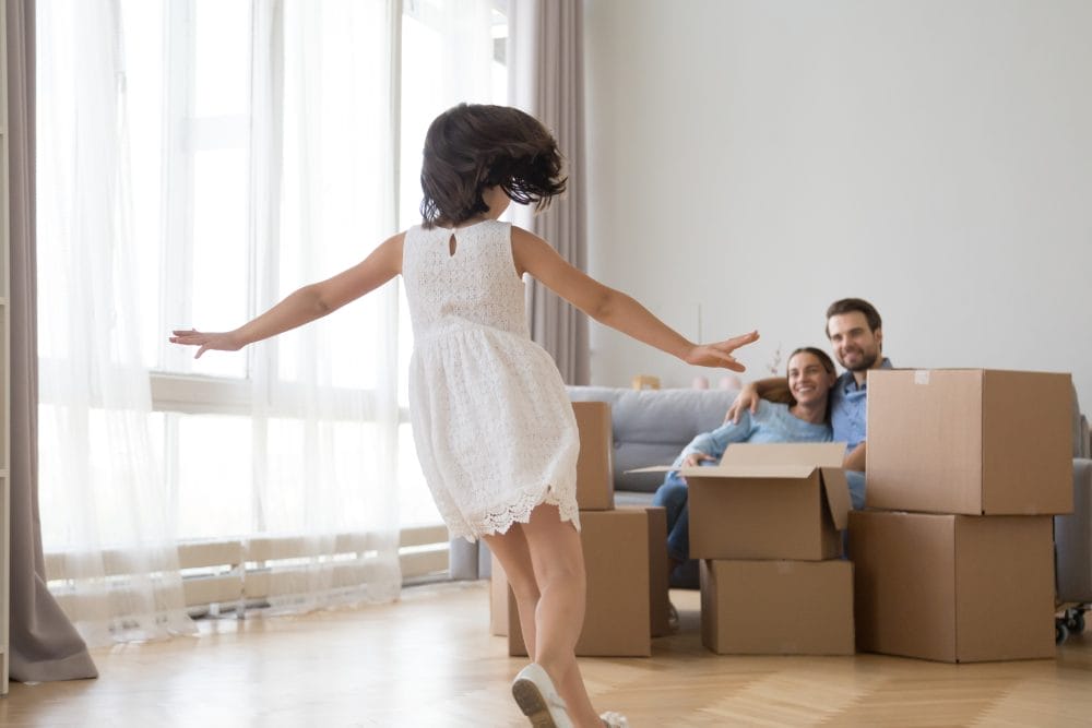 A little girl dancing in front of her parents and moving boxes