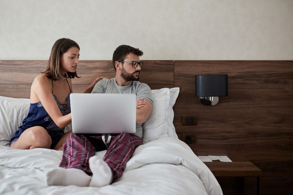 A woman upset at her boyfriend with a laptop on his lap