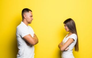 Couple looking angry at each other in front of yellow background