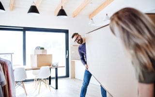 A romantic couple moving a couch into a new apartment
