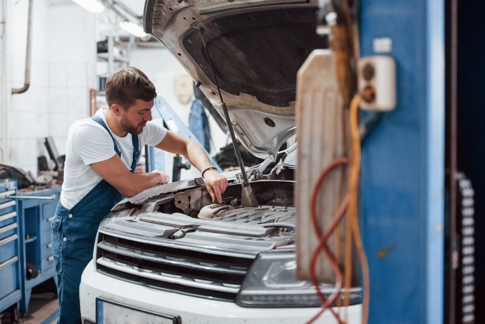 car mechanic working under the hood of a car