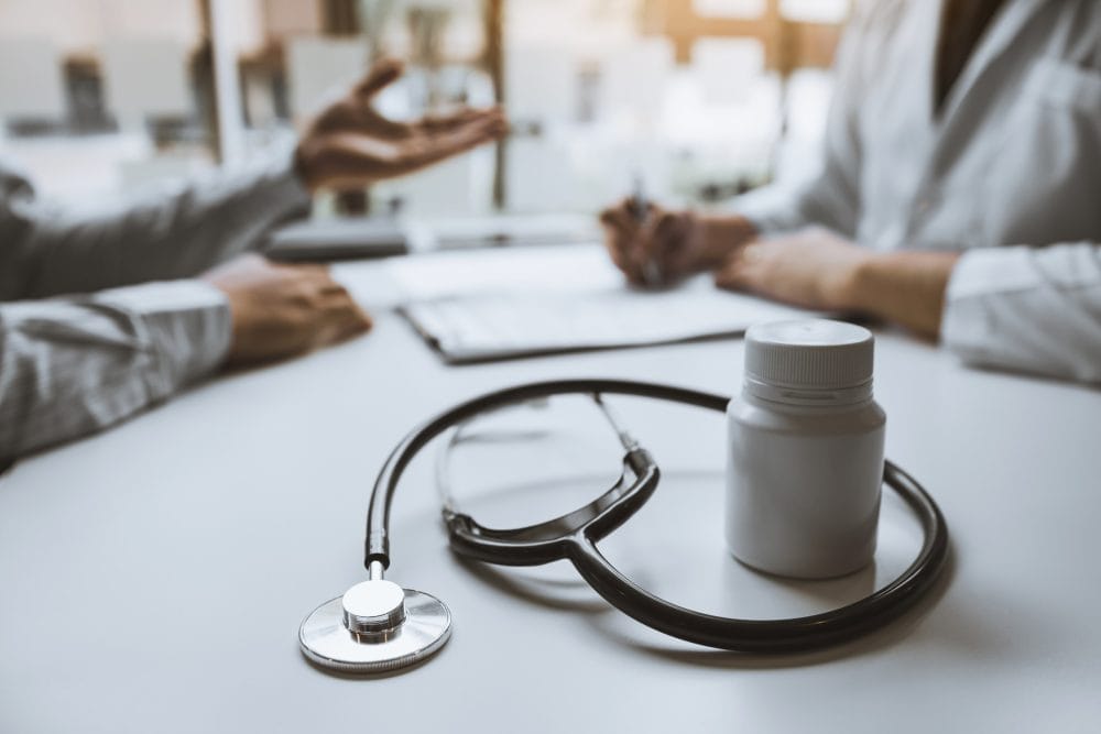 A stethoscope on a desk with a medication bottle.