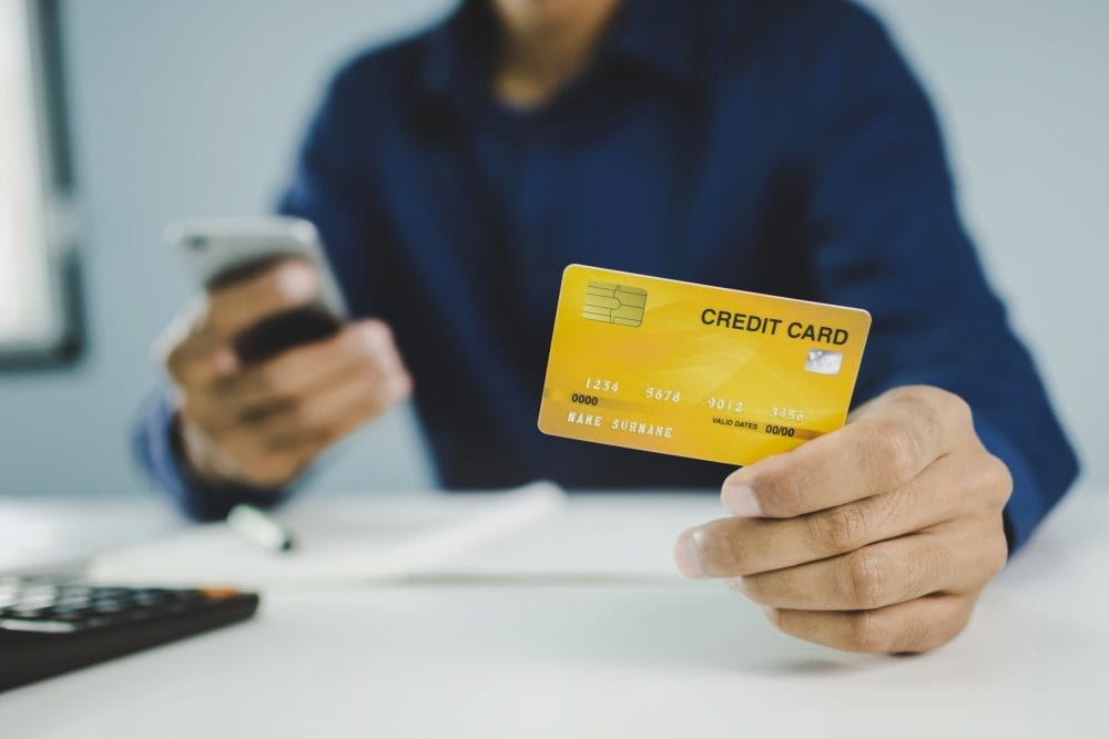 A man holding a credit card and a phone