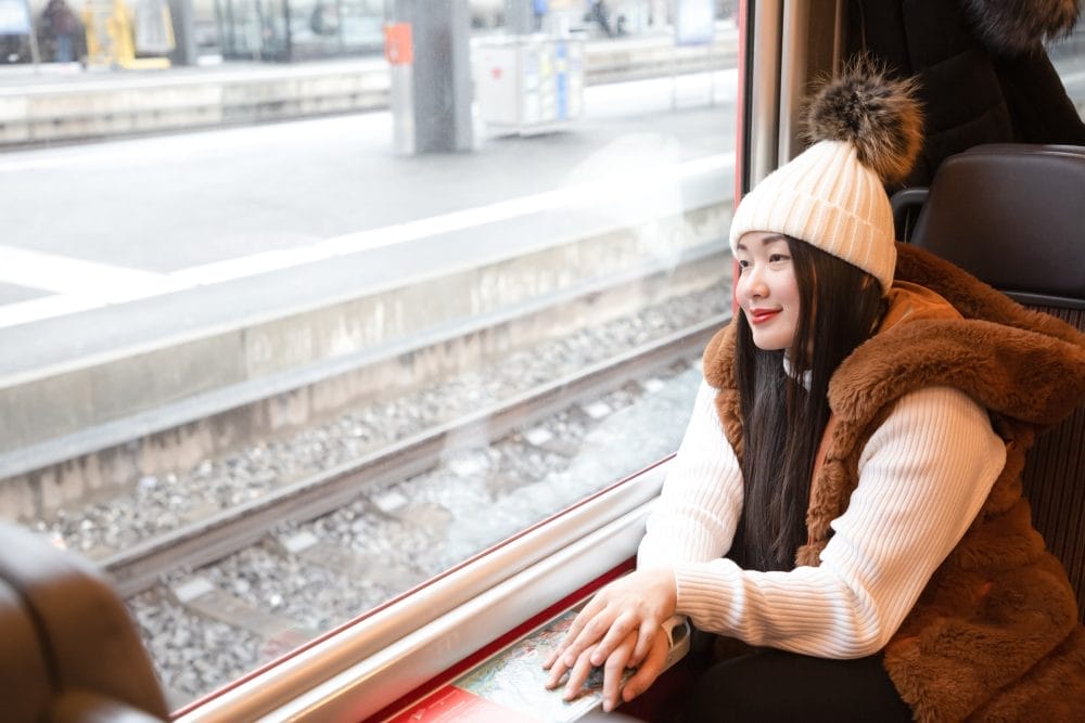Woman sitting happily on a train looking at the view outside