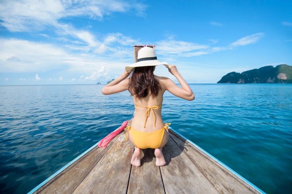 View of woman in swimsuit enjoying on thai traditional longtail Boat over beautiful mountain and ocean, Phi phi Islands, Thailand