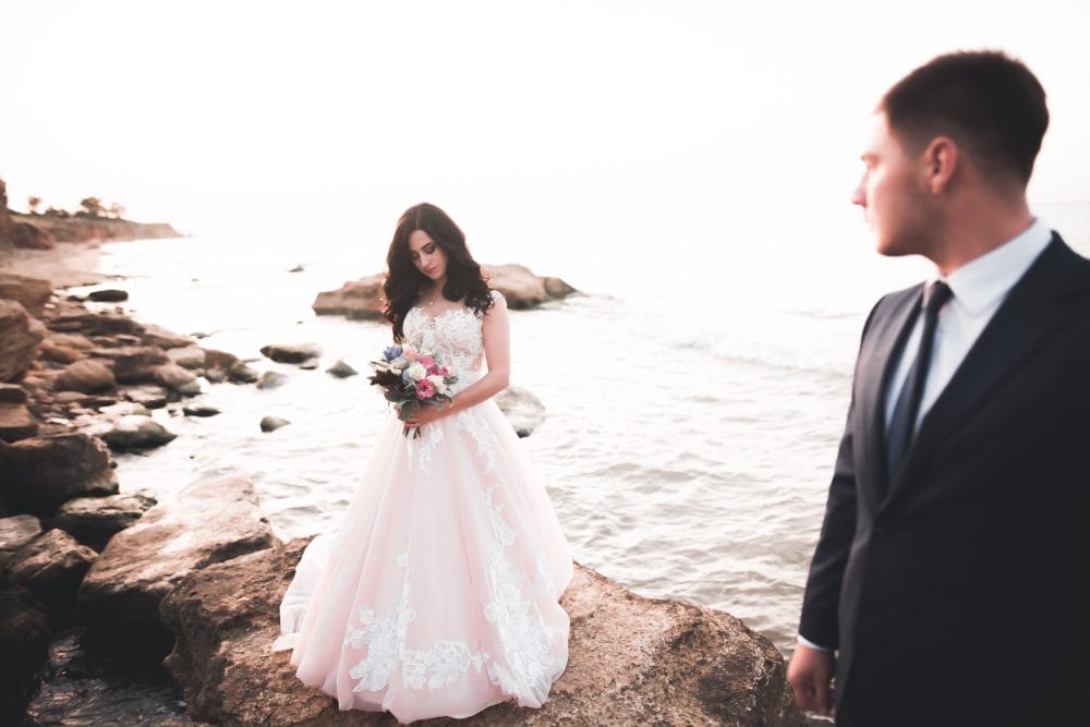 Married couple standing by the side of the ocean