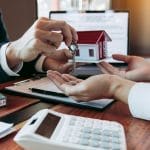 Hand of real estate agent passes the key to new homeowners in of