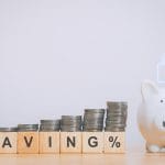 A piggy bank next to stacked coins and the work "saving" spelled in blocks