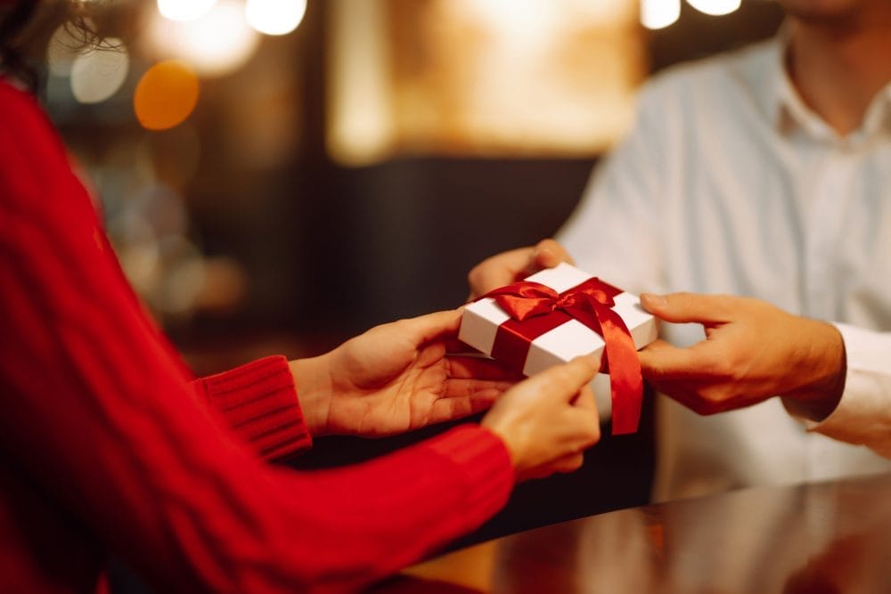 A husband givint a small gift to his wife