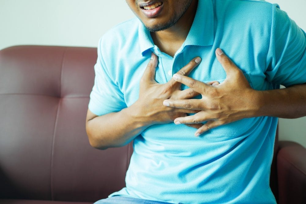 young man suffering pain in heart and holding chest with hand .