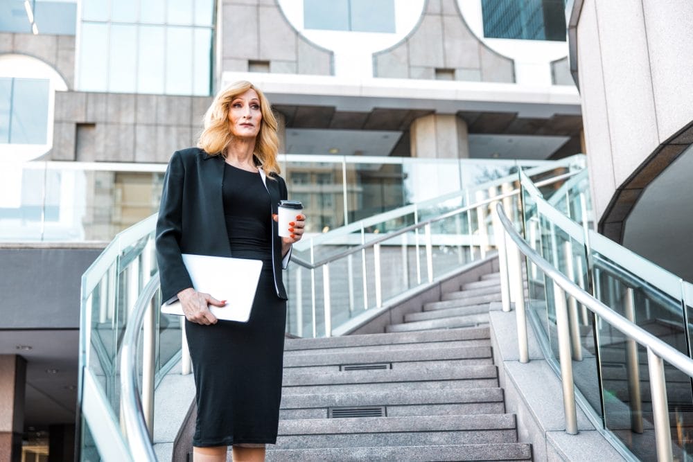 Businesswoman standing on the stairs with a cup of coffee