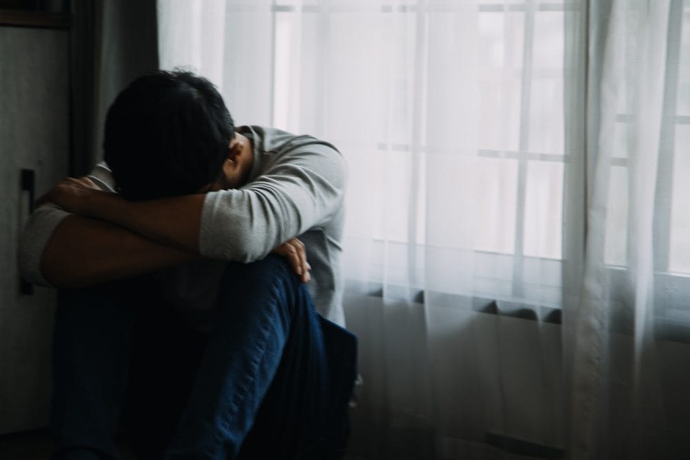 A sad man with his head on his knees