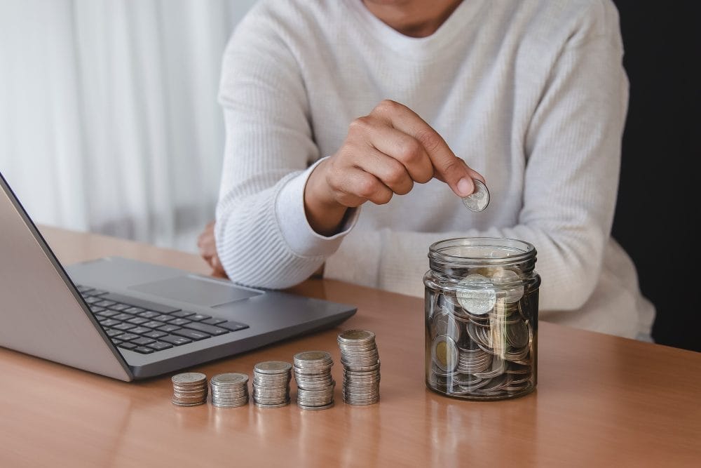 Woman stacking coins and putting them in a glass jar