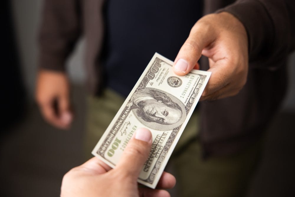 A man handing over a $100 bill