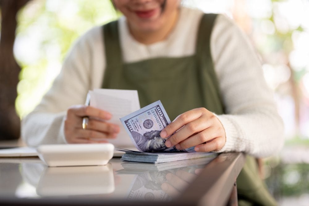 A woman paying a restaurant bill with a couple hundred dollars
