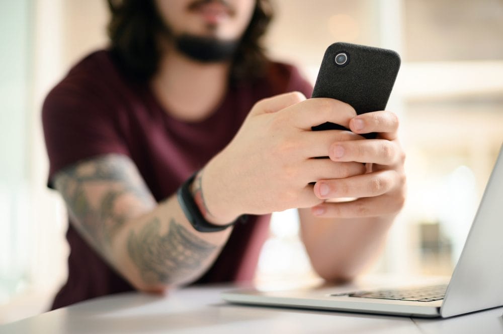 tattooed man scrolling on his smartphone