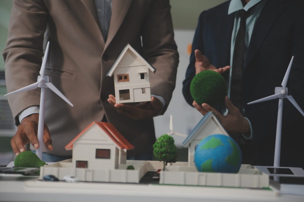 Model homes and windmills on a table with two investors