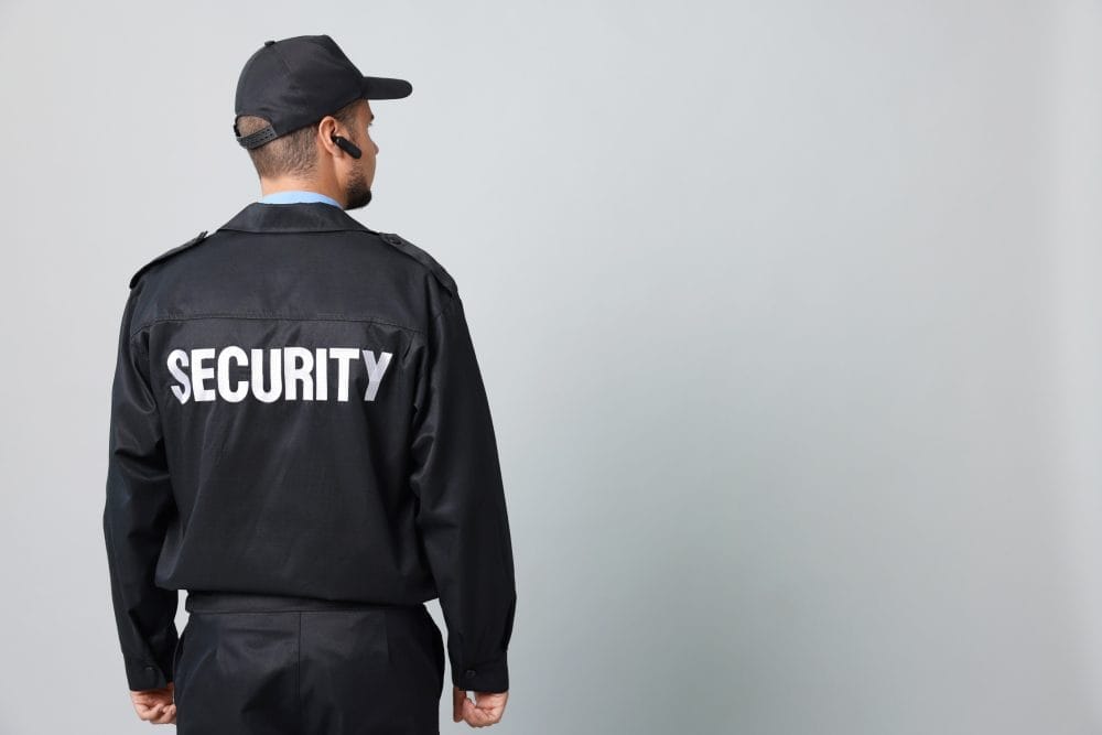 Security guard in uniform with earpiece on grey background