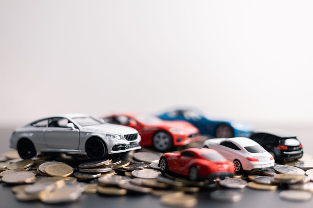Model cars sitting on a pile of coins