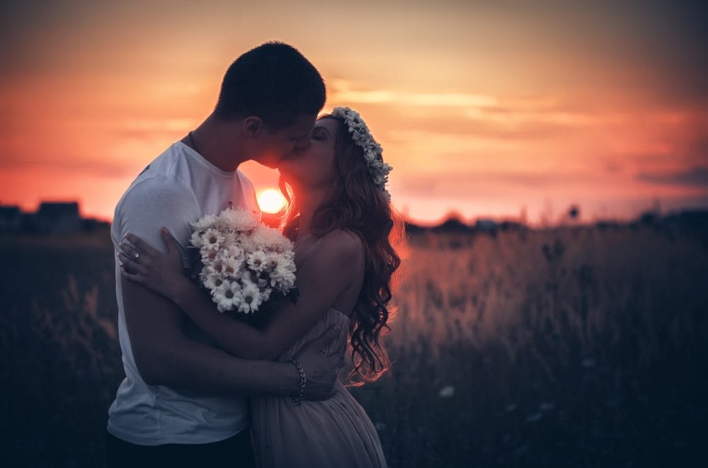 A married couple kissing as the sun goes down