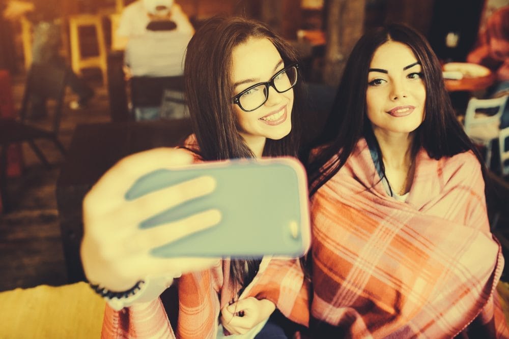 A pair of young women taking pictures for social media