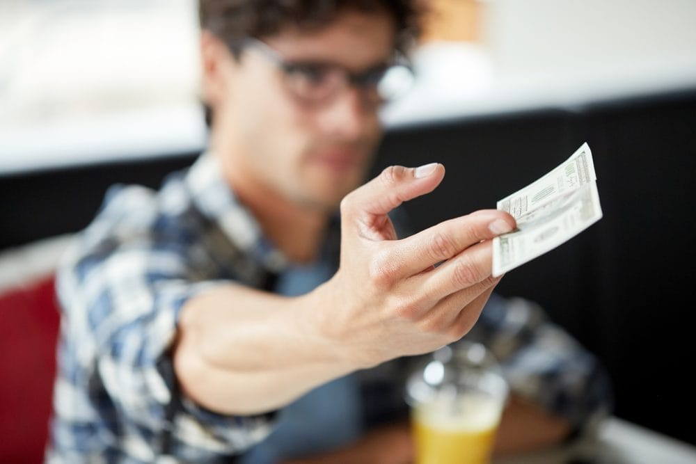 man with cash money paying at cafe