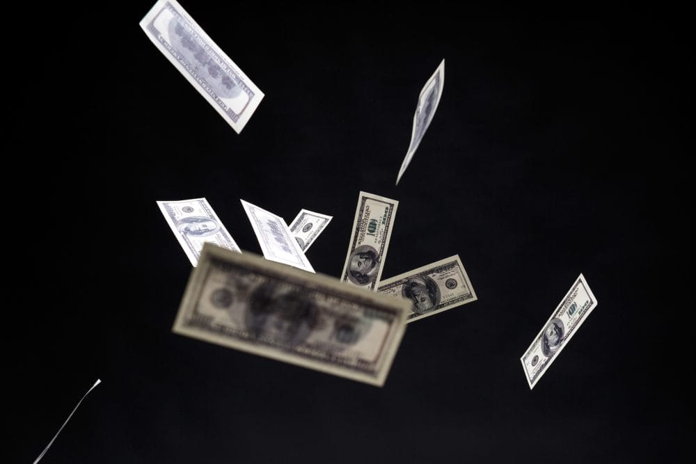 $100 bills falling in front of a black background