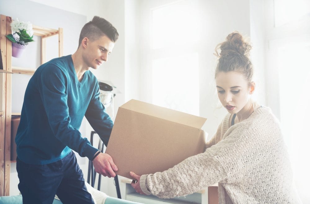 A young couple carrying a moving box