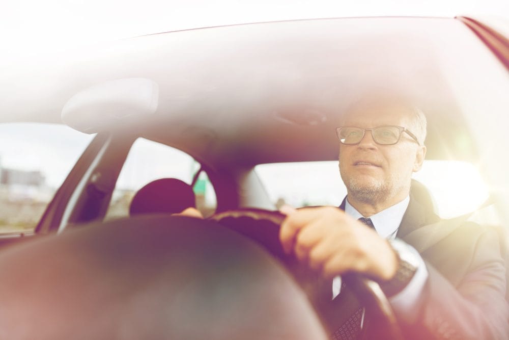 happy senior businessman driving car