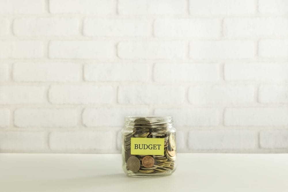 A jar filled with coins and a small sign that says "budget"