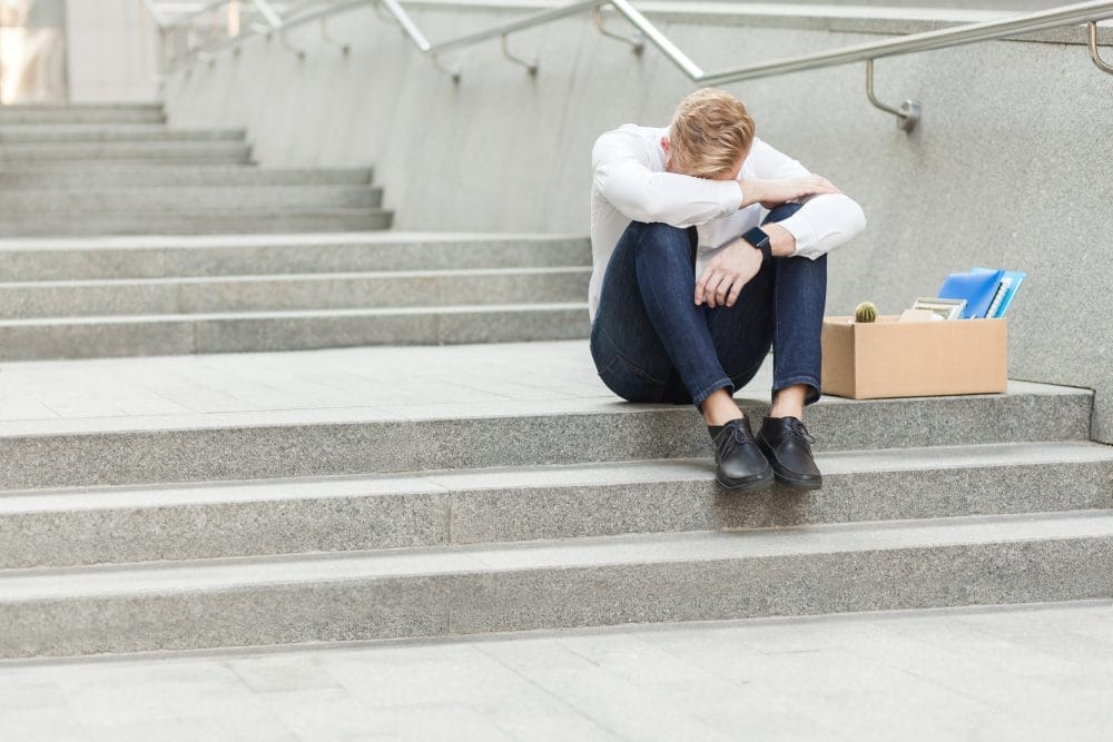 A man who has been laid off sitting on the stairs