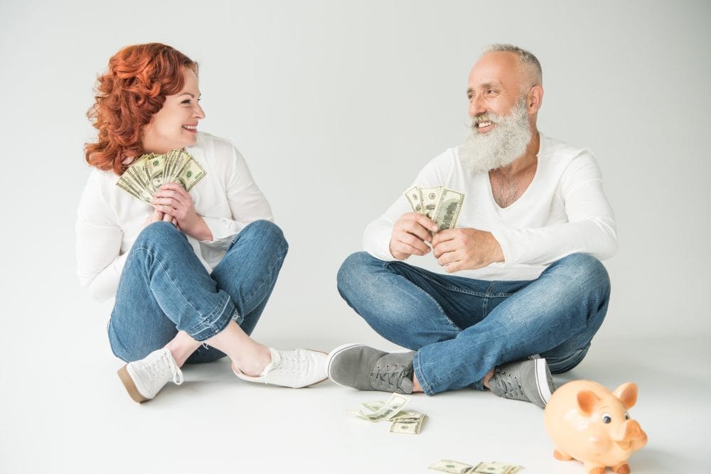Two seniors sitting down and holding money