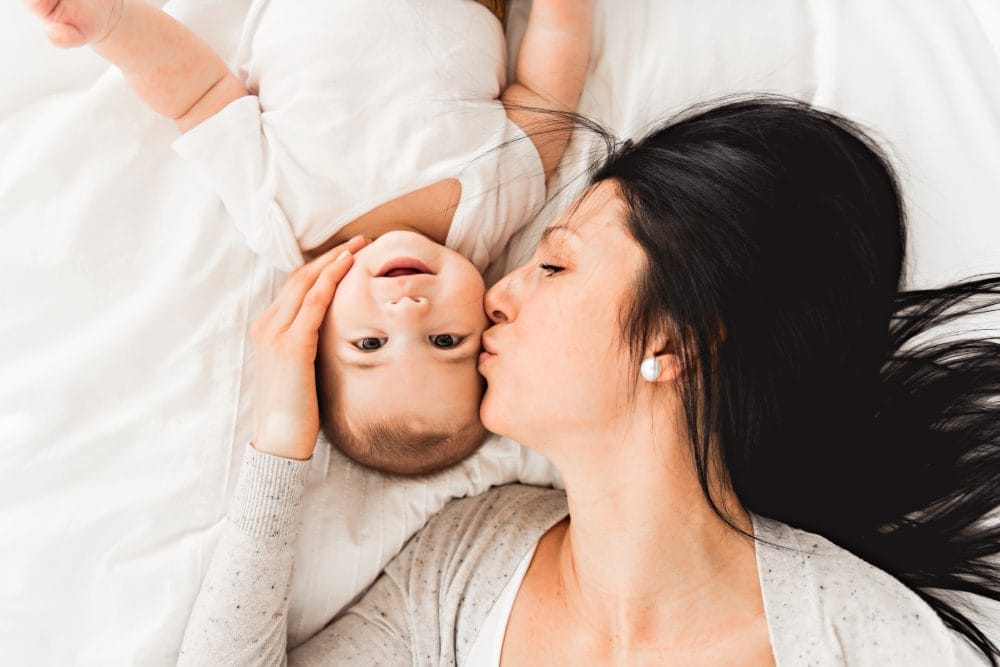 A woman with a baby on bed at home
