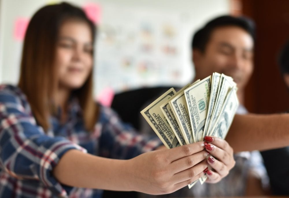 A young woman holding out cash