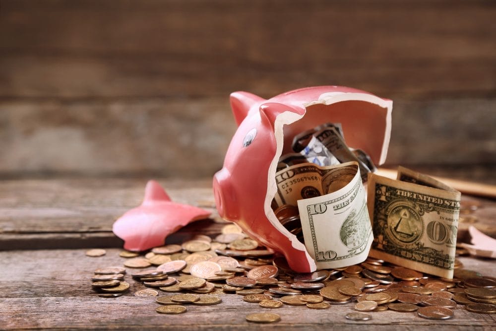 A broken piggy bank filled with money that someone earned but feels they don't deserve