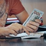 A man counting money. When you start making more money than people close to you, they can often feel betrayed