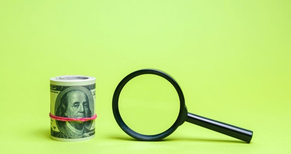 Dollars and magnifying glass. 
