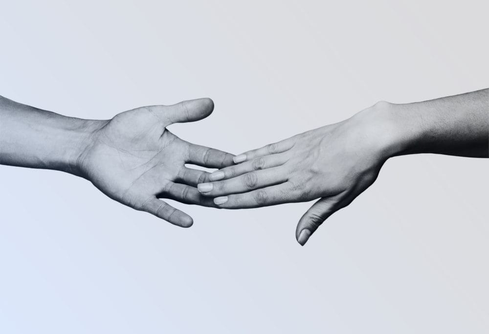 A pair of black and white hands reach out for each other