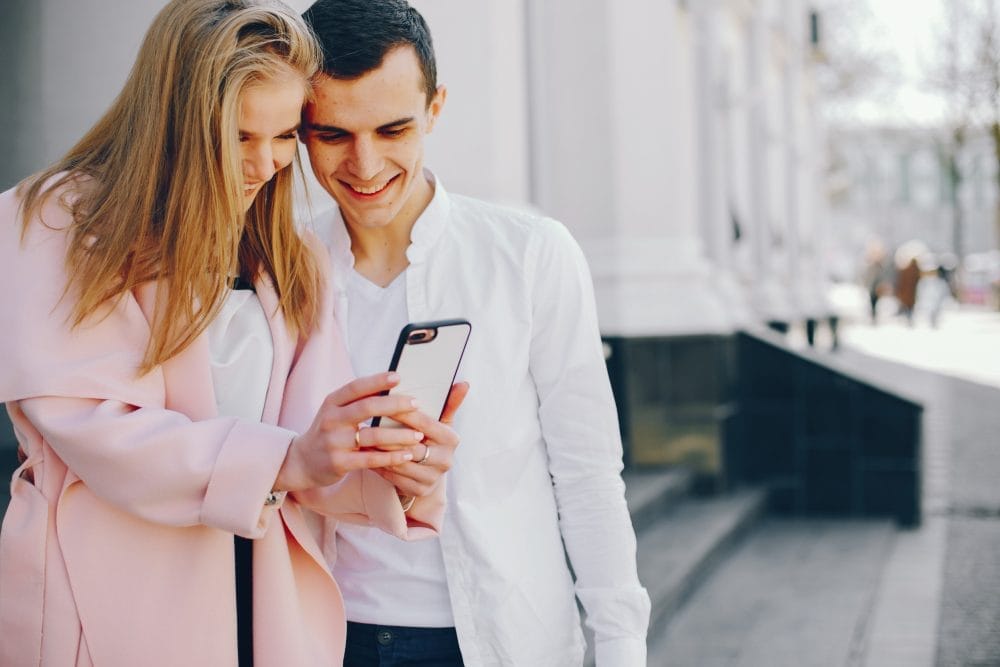 A married couple using social media together and smiling in public