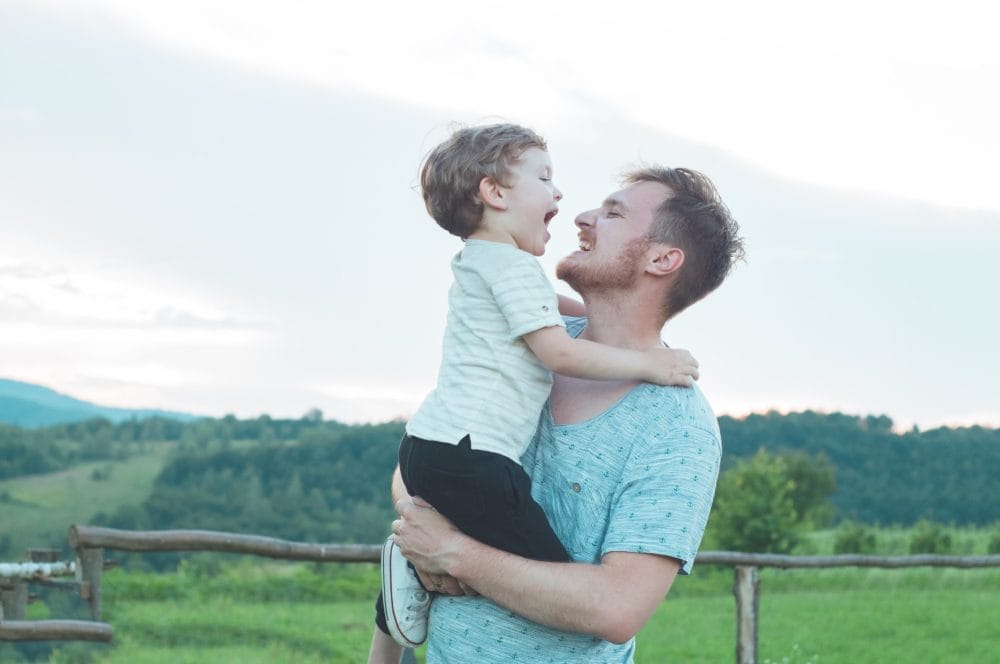 A single parent holding his son in a green field