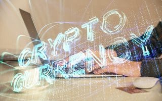 The word "cryptocurrency" projected over someone typing on a laptop