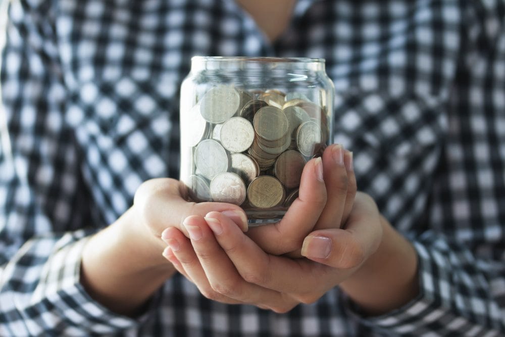 A woman holding a jar full of coins
