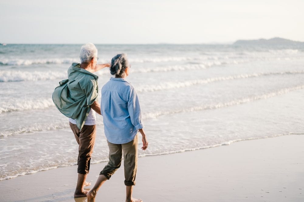 An older couple walking together on the beach