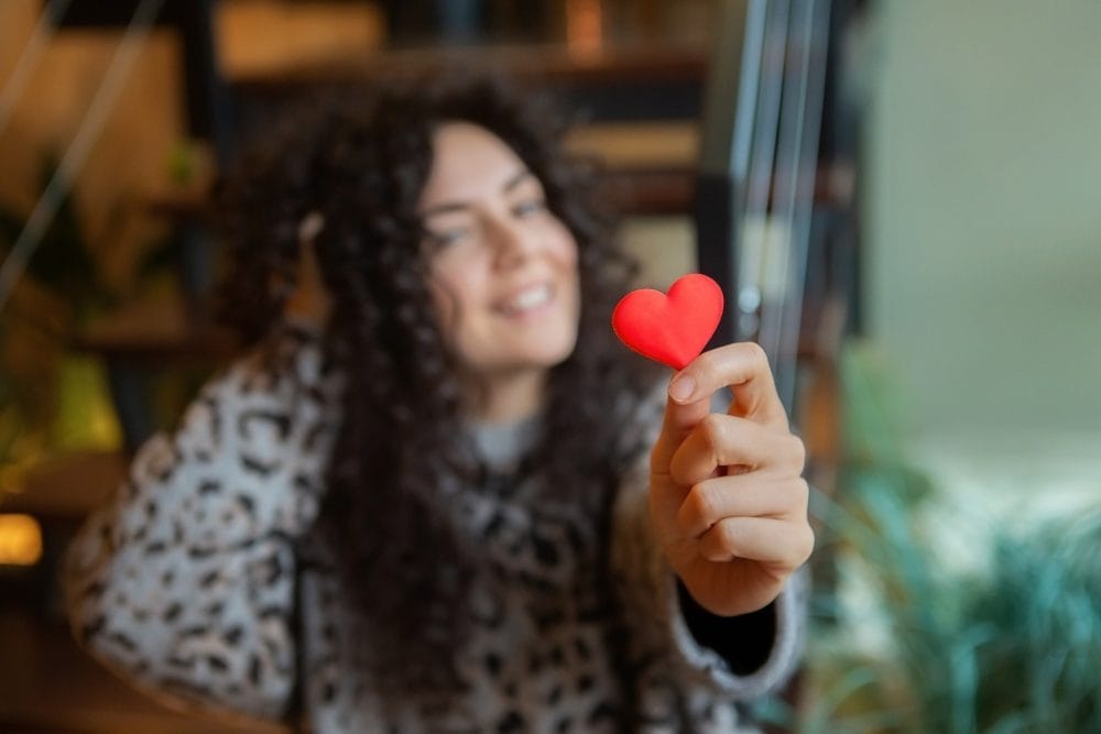 A woman who is in love handing over a red paper heart