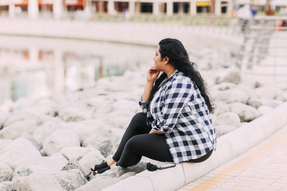A woman sitting by the water thinking quietly