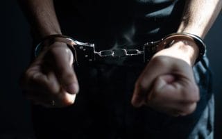 male hands in handcuffs black background