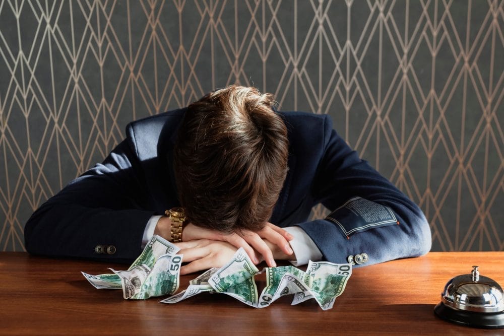 A young man with his head on his desk around cash